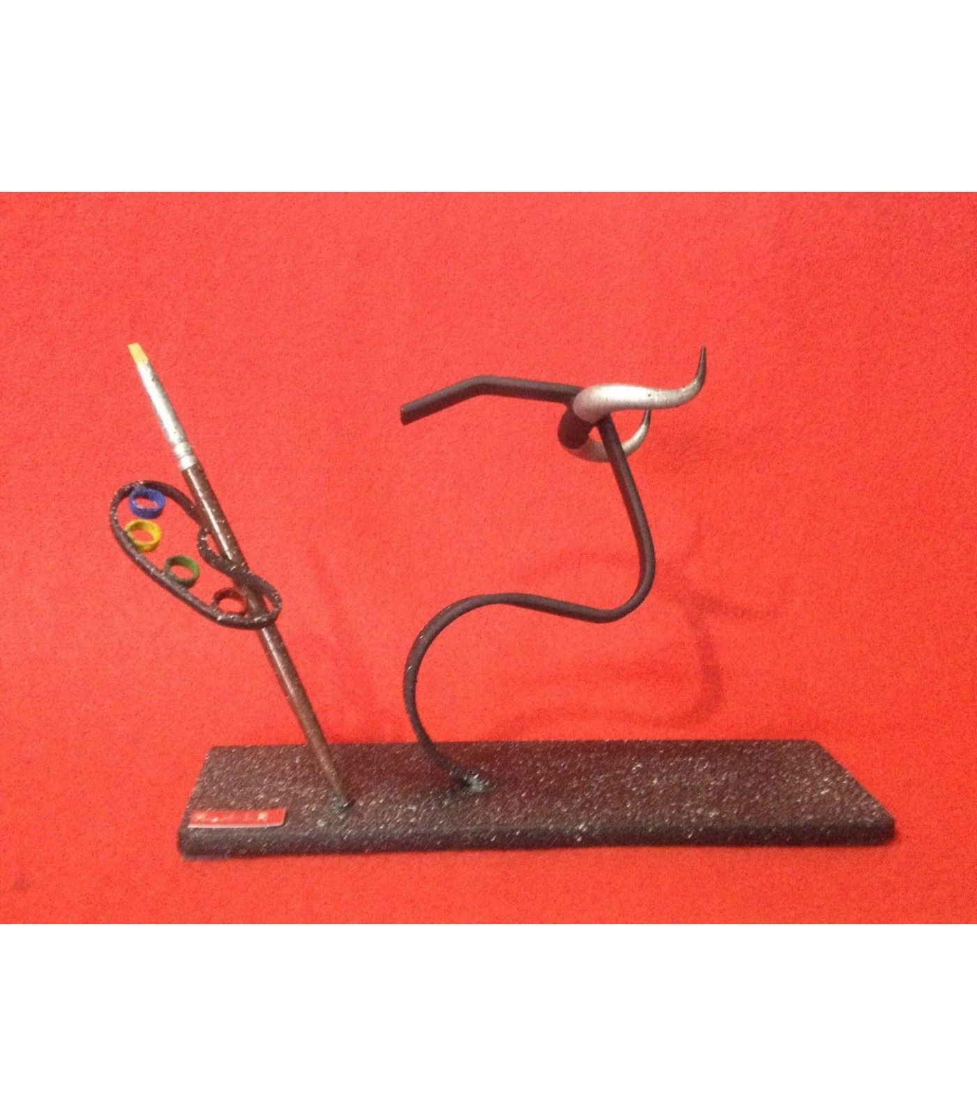 Figura taurina metálica con diseño de cabeza de toro y paleta de pintura.